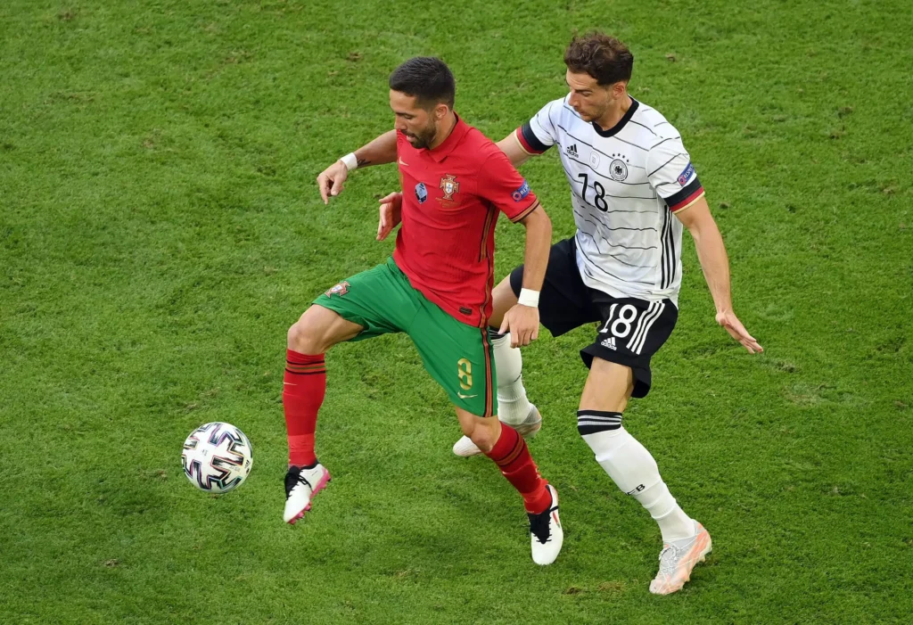 Dua tim nasional Eropa bersiap memulai pertandingan sepak bola di stadion besar dengan atmosfer penonton meriah.