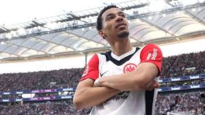 Hugo Ekitike merayakan gol dengan pose tangan bersilang di depan publik Eintracht Frankfurt.